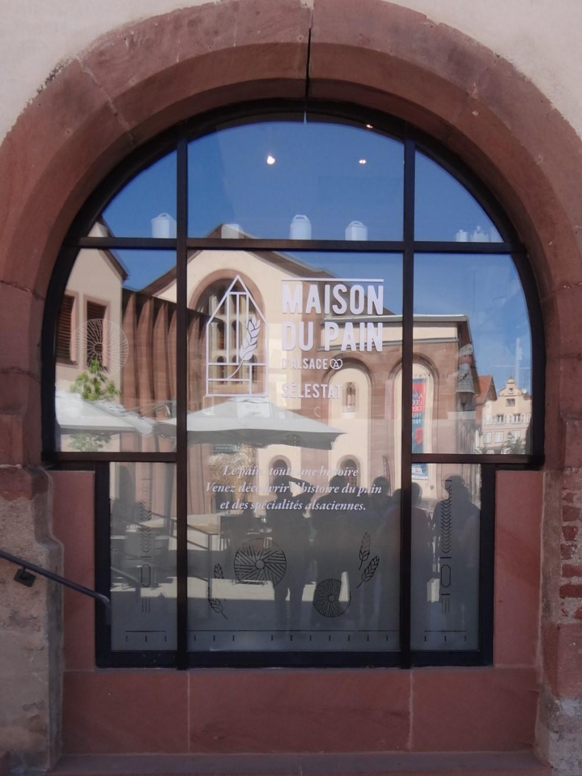 vitrine du Musée du Pain dans laquelle se mire la façade de la Bibliothèque Humaniste